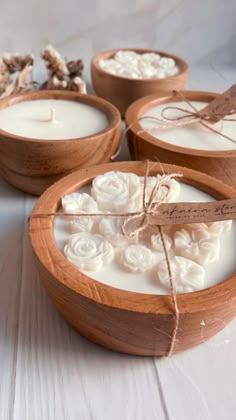 three wooden bowls filled with candles on top of a white table