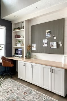 a room with white cabinets and a rug in front of the window, there is a large area rug on the floor next to the desk