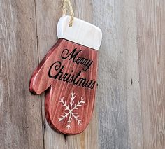 a wooden mitt ornament hanging on a wood wall with the words merry christmas written on it