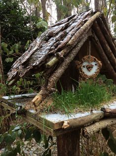 a birdhouse made out of branches and logs with a wreath hanging from the roof