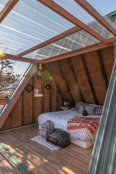 a bed sitting under a roof in a bedroom next to a wooden floor and wall