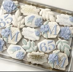 decorated cookies in the shape of flowers and leaves are displayed on a platter for a 65th birthday