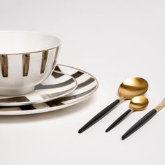 black and white striped plates with gold spoons on them next to an empty coffee cup