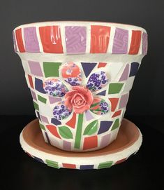 a colorful flower pot sitting on top of a plate