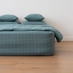 a bed sitting on top of a hard wood floor next to a wall with two pillows