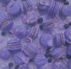 purple macaroons and blueberries are scattered on a white surface with sparkles