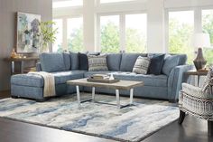 a living room with blue couches and rugs on the floor, windows in the background