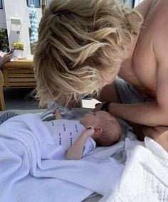 a man holding a baby in his arms while laying on top of a bed next to another person