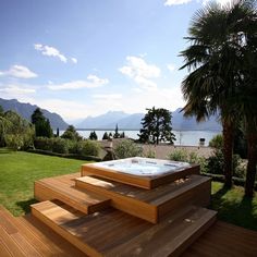 a hot tub sitting on top of a wooden deck next to a lush green field