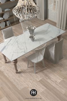 a white marble dining table with chairs and a chandelier hanging from the ceiling