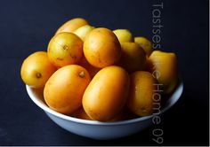 a white bowl filled with lots of oranges on top of a black countertop