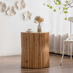 a wooden table sitting next to a white chair in front of a wall with plates on it