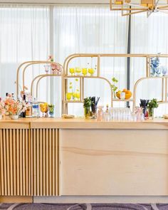 a wooden counter topped with lots of bottles and vases next to a wall filled with flowers