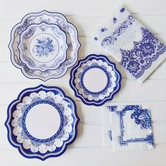 four blue and white plates sitting on top of a table next to folded napkins