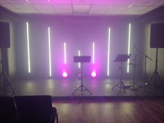 an empty room with speakers and lights on the wall, in front of a stage