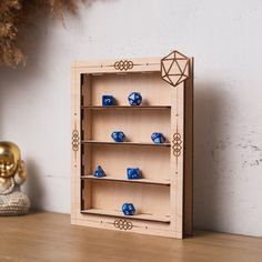 a wooden box with blue dices in it sitting on a table next to a gold statue