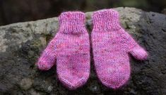 two pink mittens sitting on top of a rock