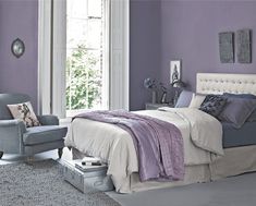 a bed room with a neatly made bed and purple walls