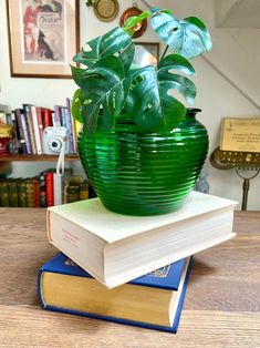 a green glass planter sitting on top of two books in front of a staircase