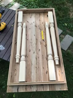 an unfinished wooden frame with some screws and nails on it, sitting in the grass