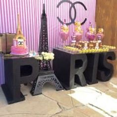 there are two tables that have candy in front of the eiffel tower on them