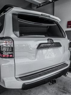 the rear end of a white toyota suv in a garage