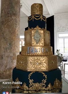 a three tiered blue and gold wedding cake with the word imagine on it's side