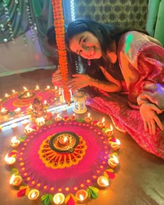 a woman sitting on the floor with candles in front of her