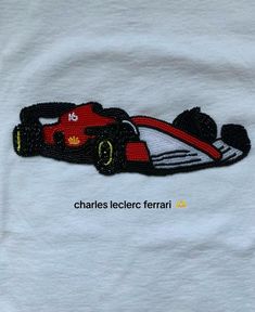 a white t - shirt with a red race car embroidered on it