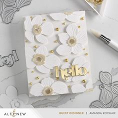 a close up of a card on a table with paper flowers and gold foil lettering