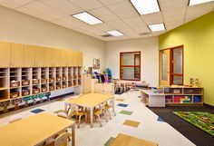 an empty classroom with tables, chairs and bookshelves on the walls is shown