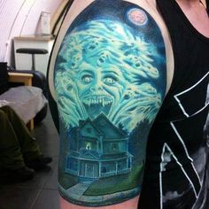 a man's arm with a scary house on it