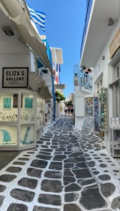 an alley way with shops and flags on the buildings in the background, surrounded by stone pavement