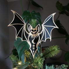 an ornament shaped like a bat hanging from a christmas tree with green leaves