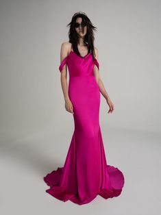 a woman in a long pink dress posing for the camera with her hands on her hips