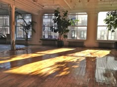 an empty room with lots of windows and wood flooring in the middle of it