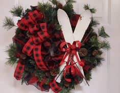 a wreath with scissors and pine cones hanging on the front door to give it a festive touch