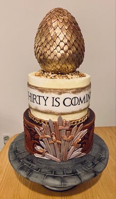 a three tiered cake decorated with gold and silver decorations