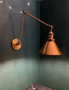 a wall light hanging from the side of a green wall