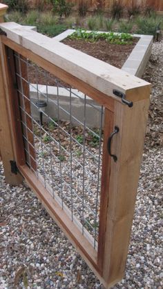 a wooden planter filled with lots of plants next to a fenced in area