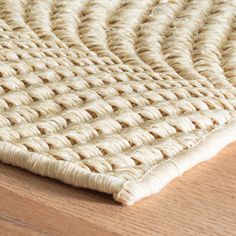 a close up view of a woven rug on a wooden floor with natural wood grain