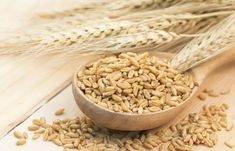 a wooden spoon filled with wheat on top of a table