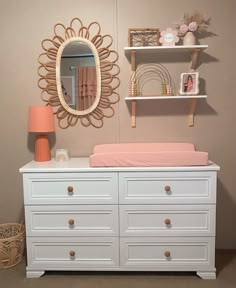 a baby's room with a dresser, mirror and shelf on the wall above it