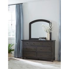 a dresser with a mirror on top of it in front of a curtained window