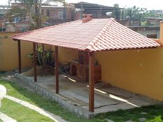 a gazebo sitting on top of a lush green field next to a yellow building