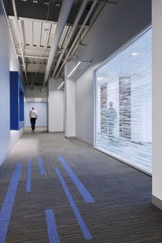 a man is walking down the hallway in an office building with blue lines painted on the floor