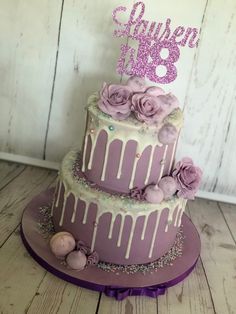 a three tiered cake with purple icing and flowers on top that says queen b