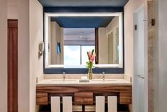 a bathroom with two white towels and a large mirror above the sink in front of it