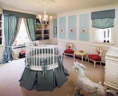 a baby's room decorated in blue and white with a rocking horse next to the crib