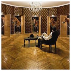 a man sitting on a chair in front of a room with mirrors and horse heads